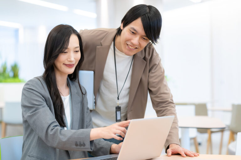 ノートパソコンの画面を囲んで打ち合わせをするチーム